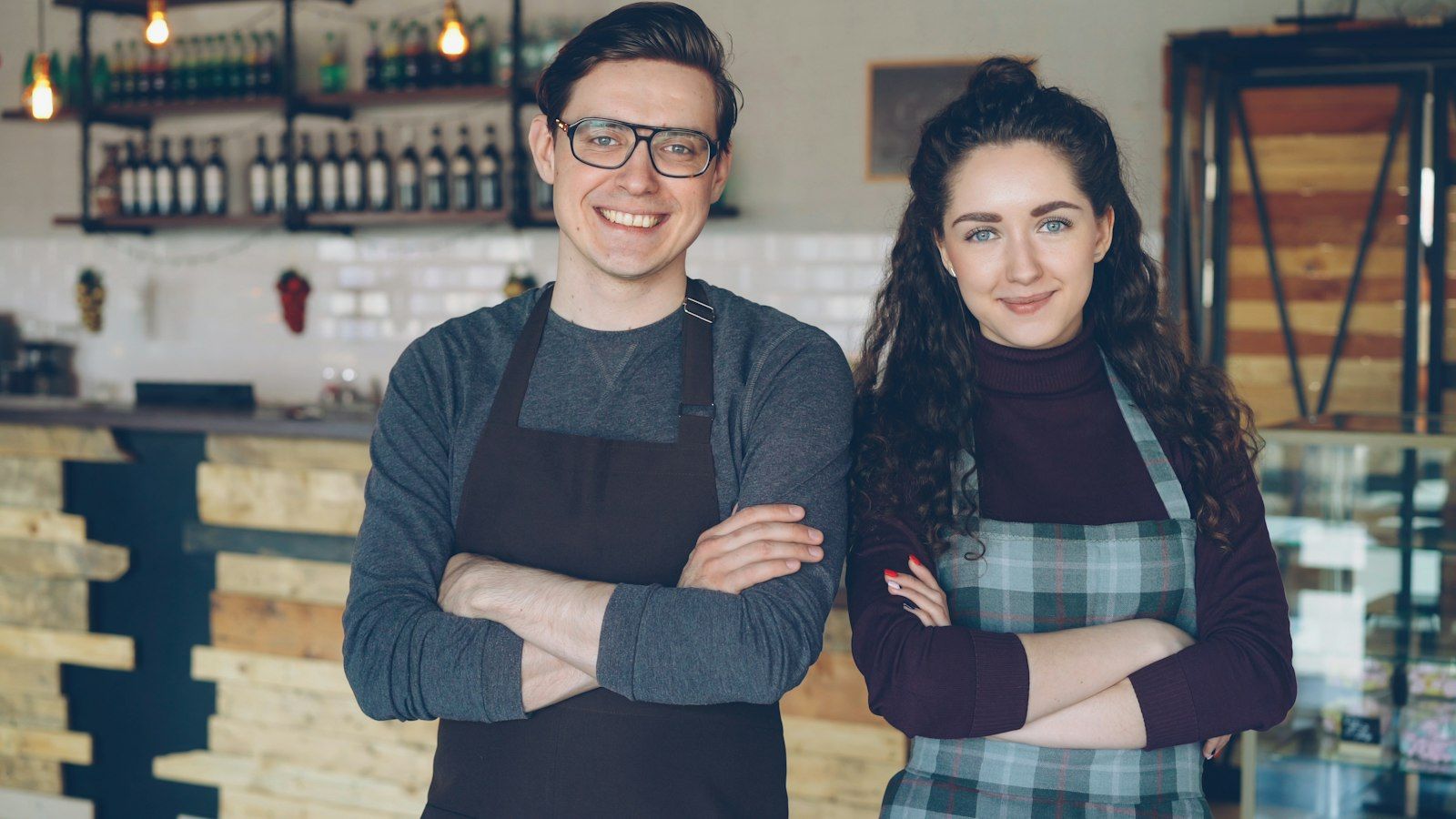 Zwei Café-Inhaber stehen mit verschränkten Armen in ihrem Laden